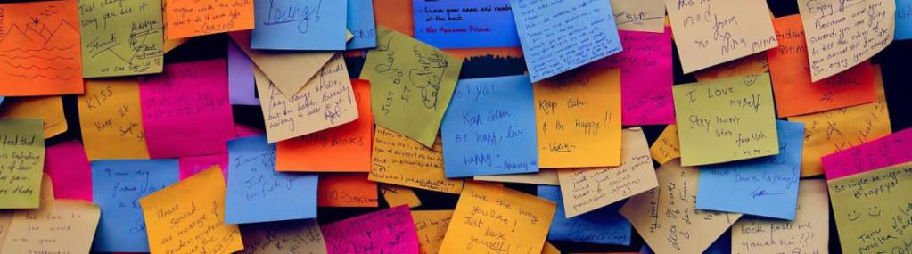 Kleine Post-It-Zettel an einer Wand angeheftet